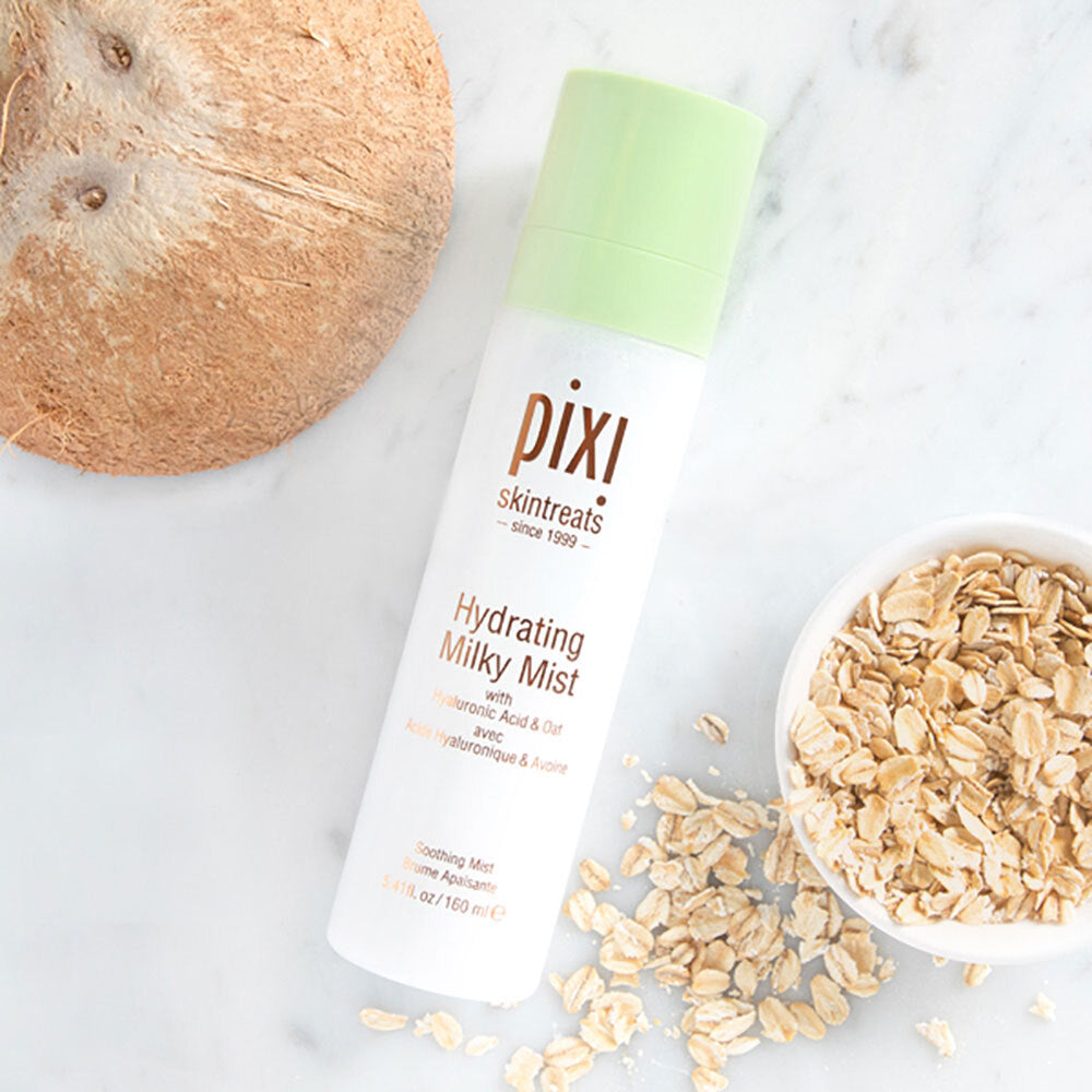 Pixi Hydrating Milky Mist bottle with a coconut and oats on a marble surface