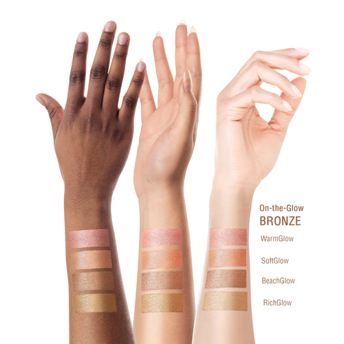 Three human forearms and hands are shown against a white background, each with four rectangular makeup swatches stacked near the lower arm. The swatches represent warm skin-tone makeup shades labeled On-the-Glow BRONZE, with variants WarmGlow, SoftGlow, BeachGlow, and RichGlow listed on the right. view 2