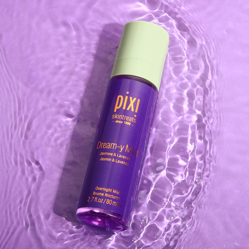 A bottle of PIXI Dream-y Mist sleep spray on a purple background with water ripples around it, indicating movement and freshness. view 1